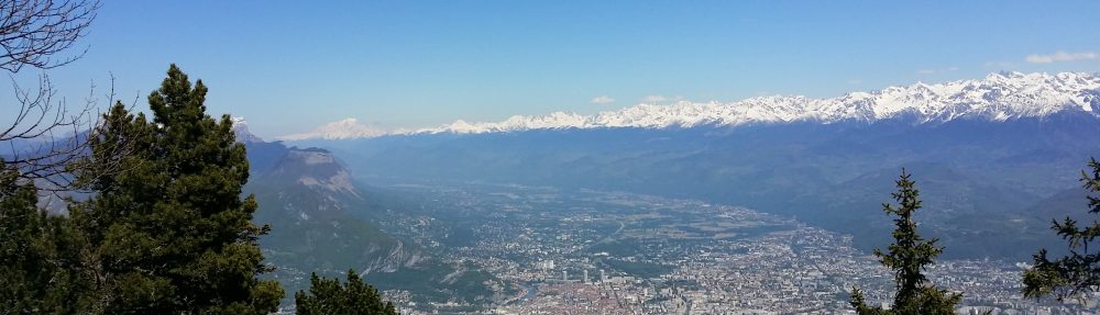 Vue panoramique de la vallée de Grenoble et des massifs alpins depuis les hauteurs.
